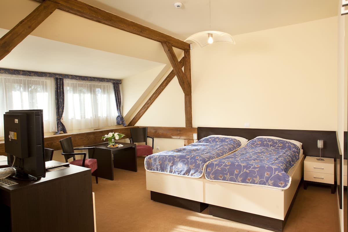 Een slaapkamer met een bed, bureau, stoel en een klein tafeltje met een plant.
