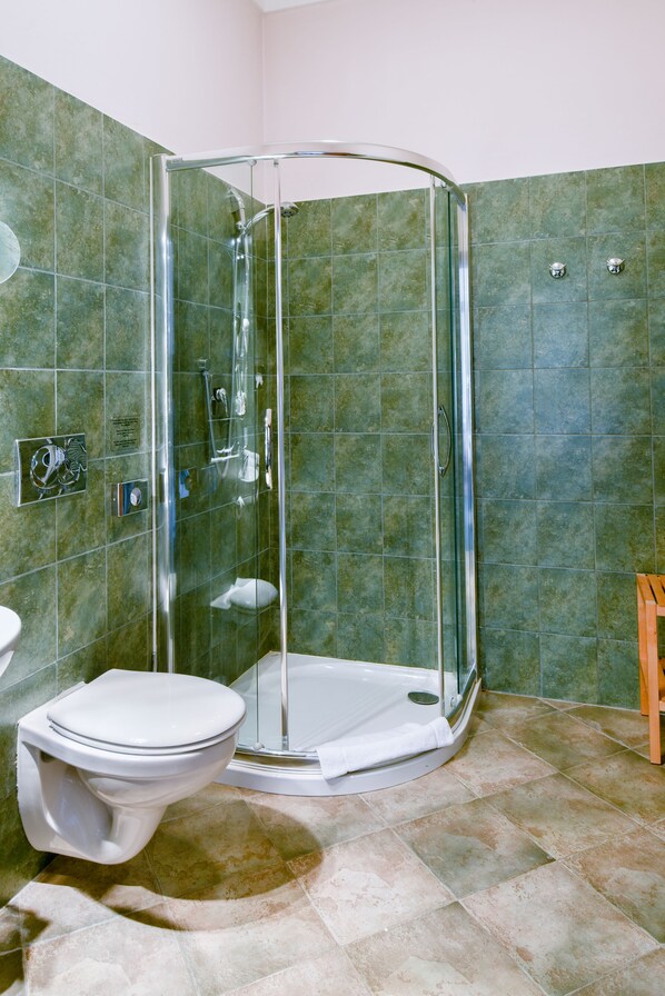 Un baño con ducha envuelta en vidrio, inodoro y lavamanos.
