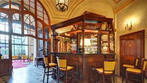 Un espace bar doté d’un comptoir en bois, de plusieurs chaises et d’une grande fenêtre offrant une vue panoramique.