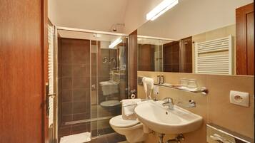A modern bathroom with a glass-enclosed shower, two sinks, and a large mirror.