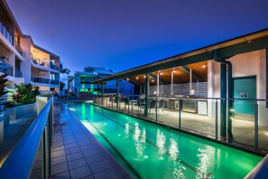 A modern hotel with a swimming pool, outdoor seating, and a covered area with tables and chairs. - Coolum Seaside (Coolum Beach)