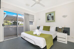 A hotel room with a bed, a nightstand, a ceiling fan, a sliding glass door, and a framed picture on the wall. - Coolum Seaside (Coolum Beach)