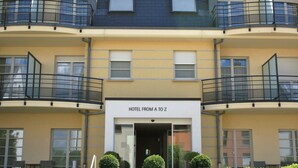 Un hotel de varios pisos con balcones, un cartel que dice "HOTEL FROM A TO Z" y una entrada de cristal.