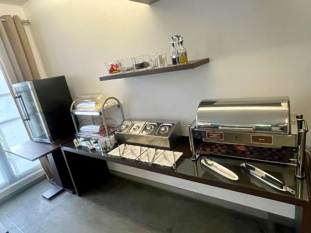 Een zelfbedieningsontbijtbuffet met koffieautomaten, sau dispensers en servetten.