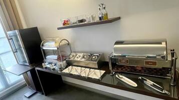 Een zelfbedieningsontbijtbuffet met koffieautomaten, sau dispensers en servetten.