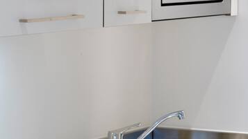 A kitchen with a stainless steel sink, a microwave, and a stove with two burners.