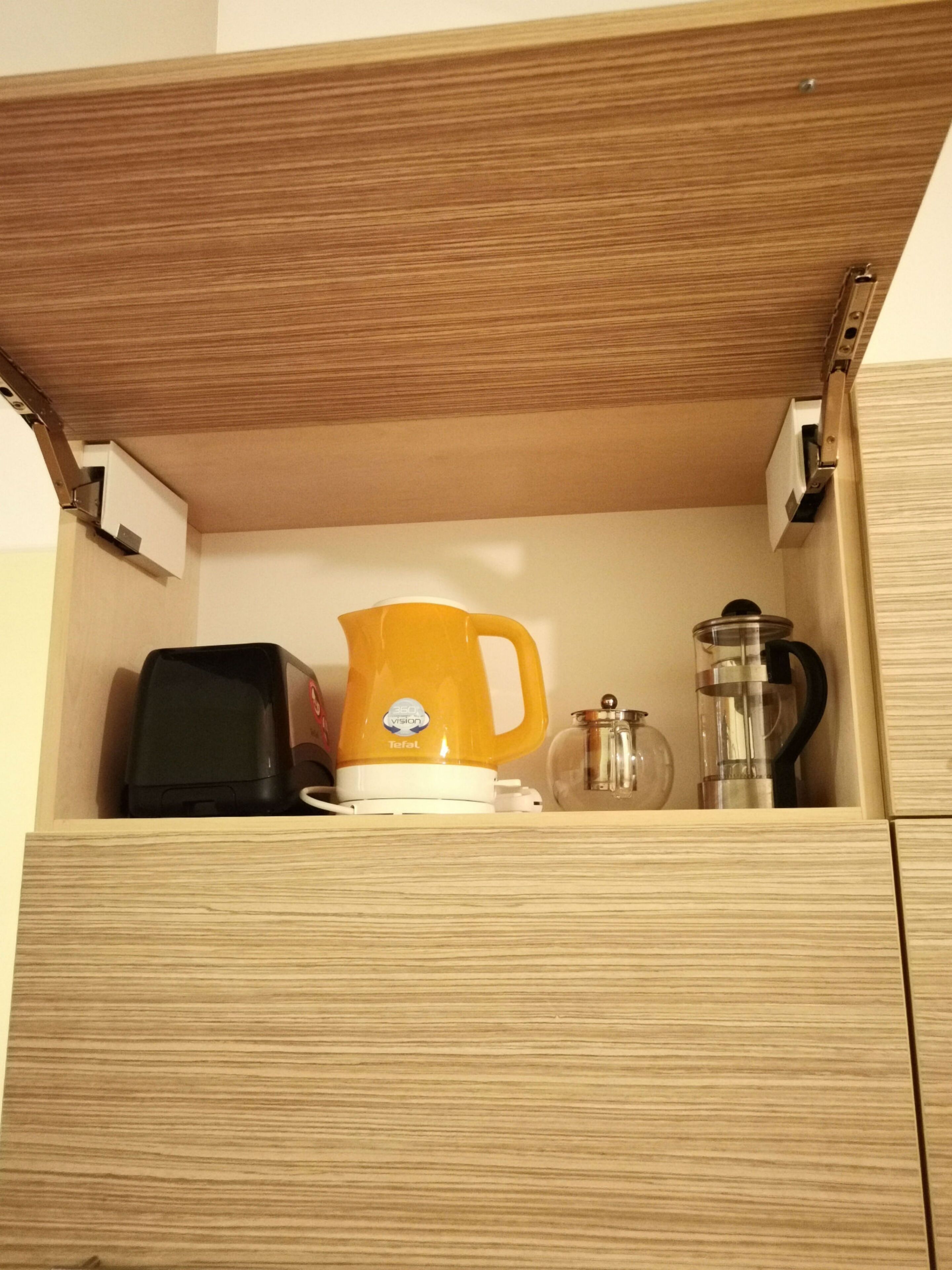 Un tiroir en bois contenant une cafetière jaune, un appareil électronique noir et un récipient en verre.