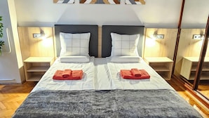 Moderni hotellihuone, jossa on suuri sänky, kaksi yöpöytää, peili ja geometrisesti kuvioitu seinäkoriste.