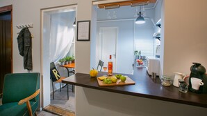 A kitchen with a wooden countertop, a chair, a table with a plant, and a window. - Friends Hostel and Apartments Budapest (Budapest)