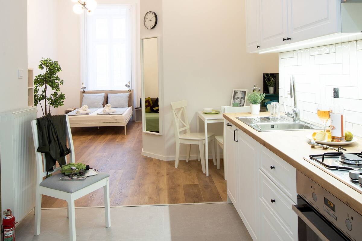 A modern kitchen with white cabinetry, a dining area with a table and chairs, and a cozy seating area with a bench.
