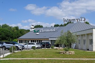 Un motel con un letrero que dice "Clermotel" y un estacionamiento con varios autos.