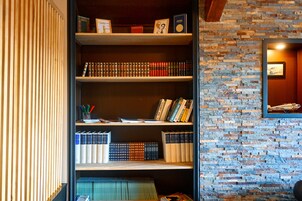 Una estantería con libros y objetos decorativos frente a un muro de ladrillo.