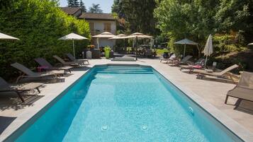 Relax by the pool surrounded by lush greenery and comfortable lounge chairs.