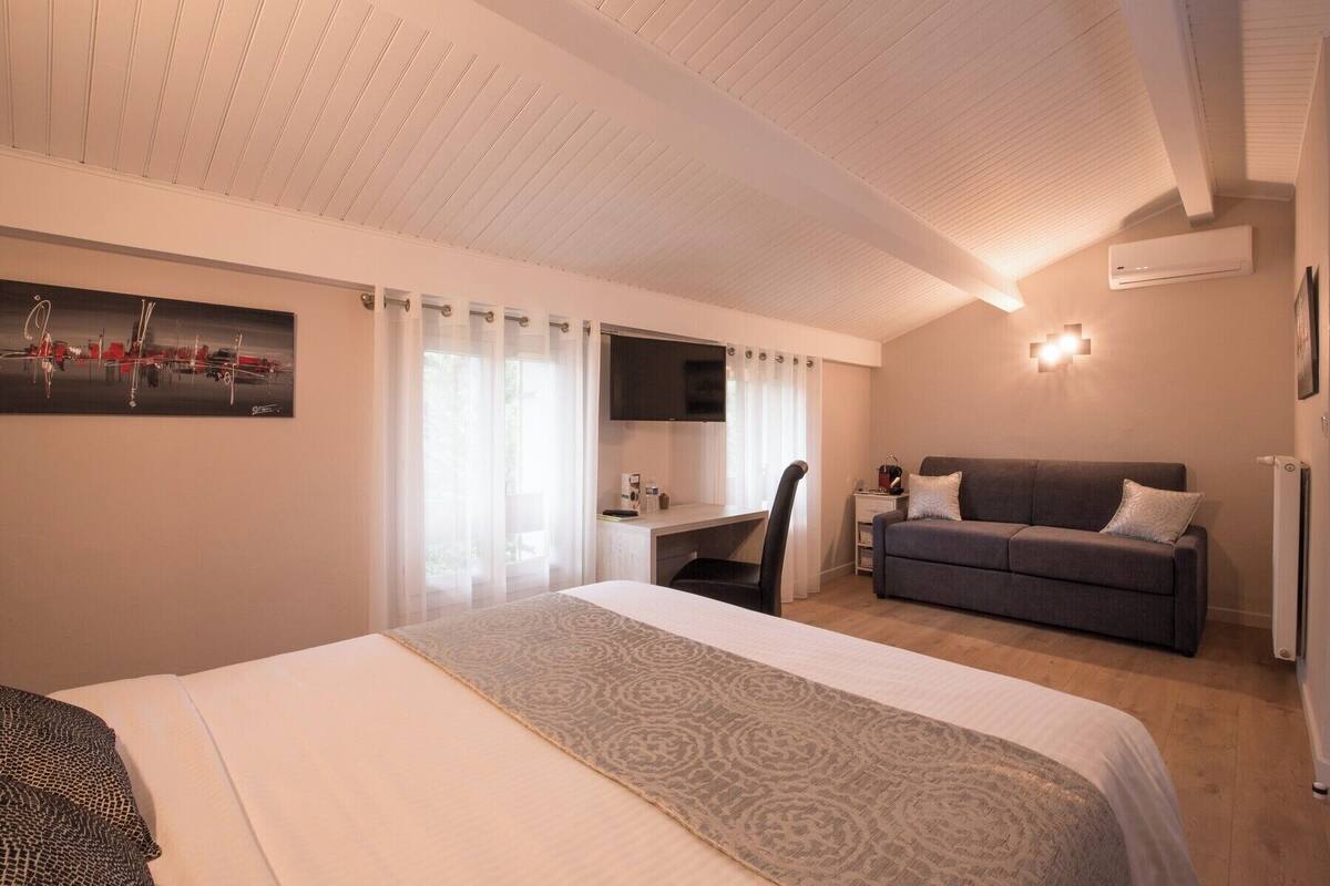 Una habitación de hotel con cama, escritorio, sofá y televisión.