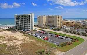 Um hotel à beira-mar com vários andares, estacionamento e vista para a praia e oceano.