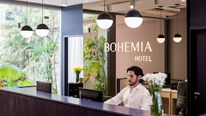 Ein moderner Empfangstresen, ein großes Fenster mit Pflanzen und der Schriftzug "BOHEMIA HOTEL" an der Wand.