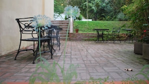 Eine Terrasse mit Sitzgelegenheit, einem Topfpflanzen und einem Pflasterweg.