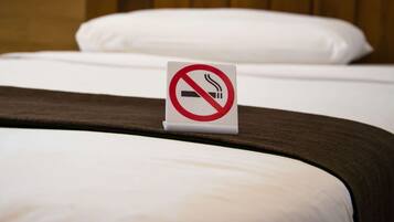 A bed with a no-smoking sign on the headboard.