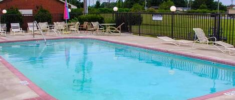 Una piscina al aire libre, sillones reclinables de piscina