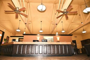 A reception area with a wooden reception desk, ceiling fans, pendant lights, and a framed picture on the wall. - Fortune Inn And Suites Newport (Newport)