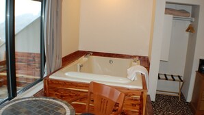 Un baño con una bañera de madera, una silla y una pequeña mesa redonda.