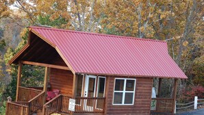 Una pequeña cabaña de madera con techo rojo, un porche y un letrero que indica que es una oficina.