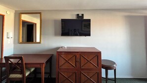 A room with a wooden desk, a chair, a television mounted on the wall, and a mirror. - Royal Inn Linden (Linden)