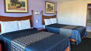 A hotel room with two beds, each with a wooden headboard, a nightstand, and a wall-mounted phone. - Royal Inn Linden (Linden)
