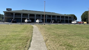 A motel with a central parking area, multiple balconies, and a clear sky. - Riverfront Lodge (Burkesville)