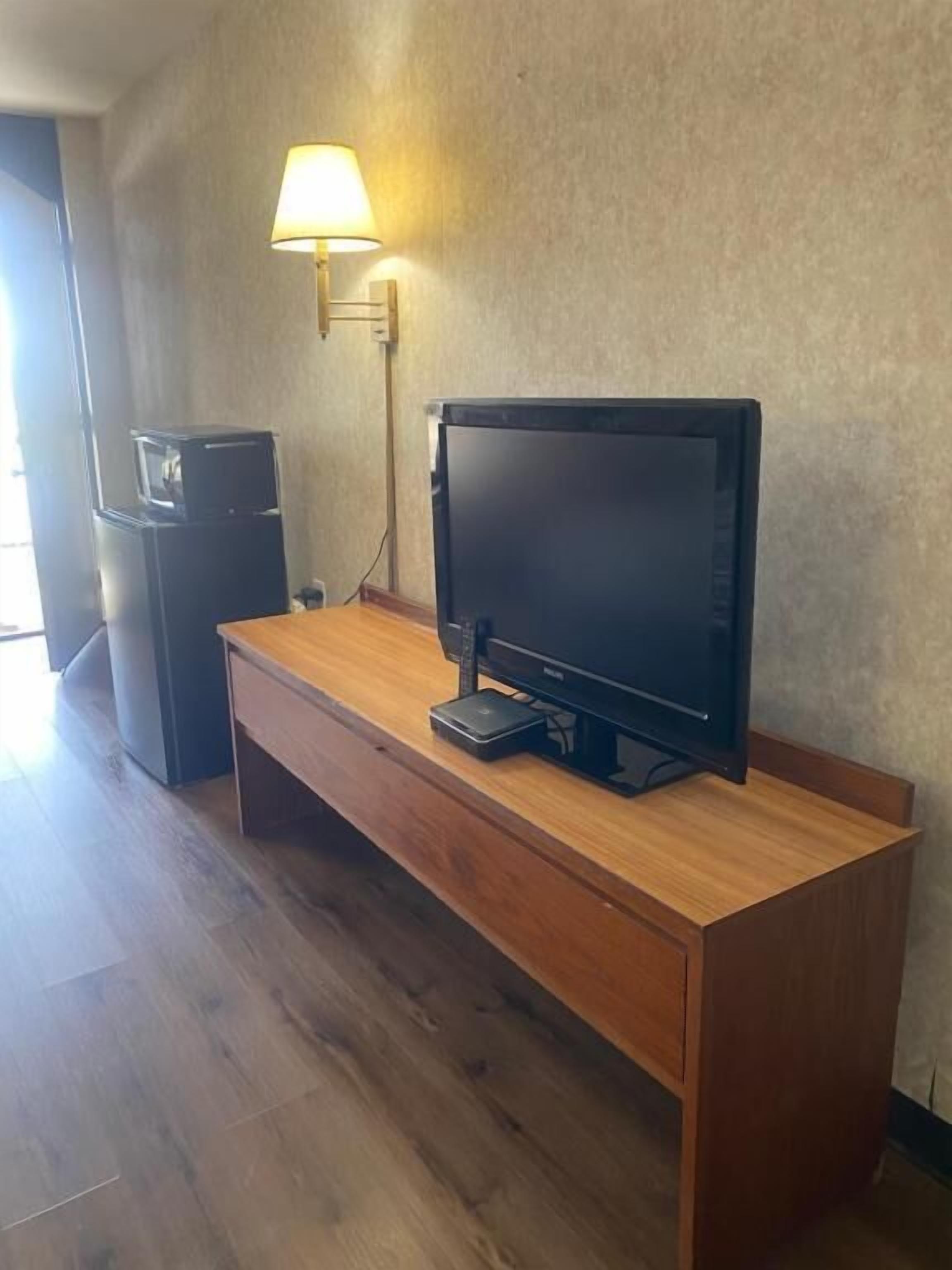 A wooden entertainment unit with a television, a lamp, and a speaker.