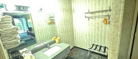 A bathroom with a sink, mirror, towel rack, and a view of the outside.