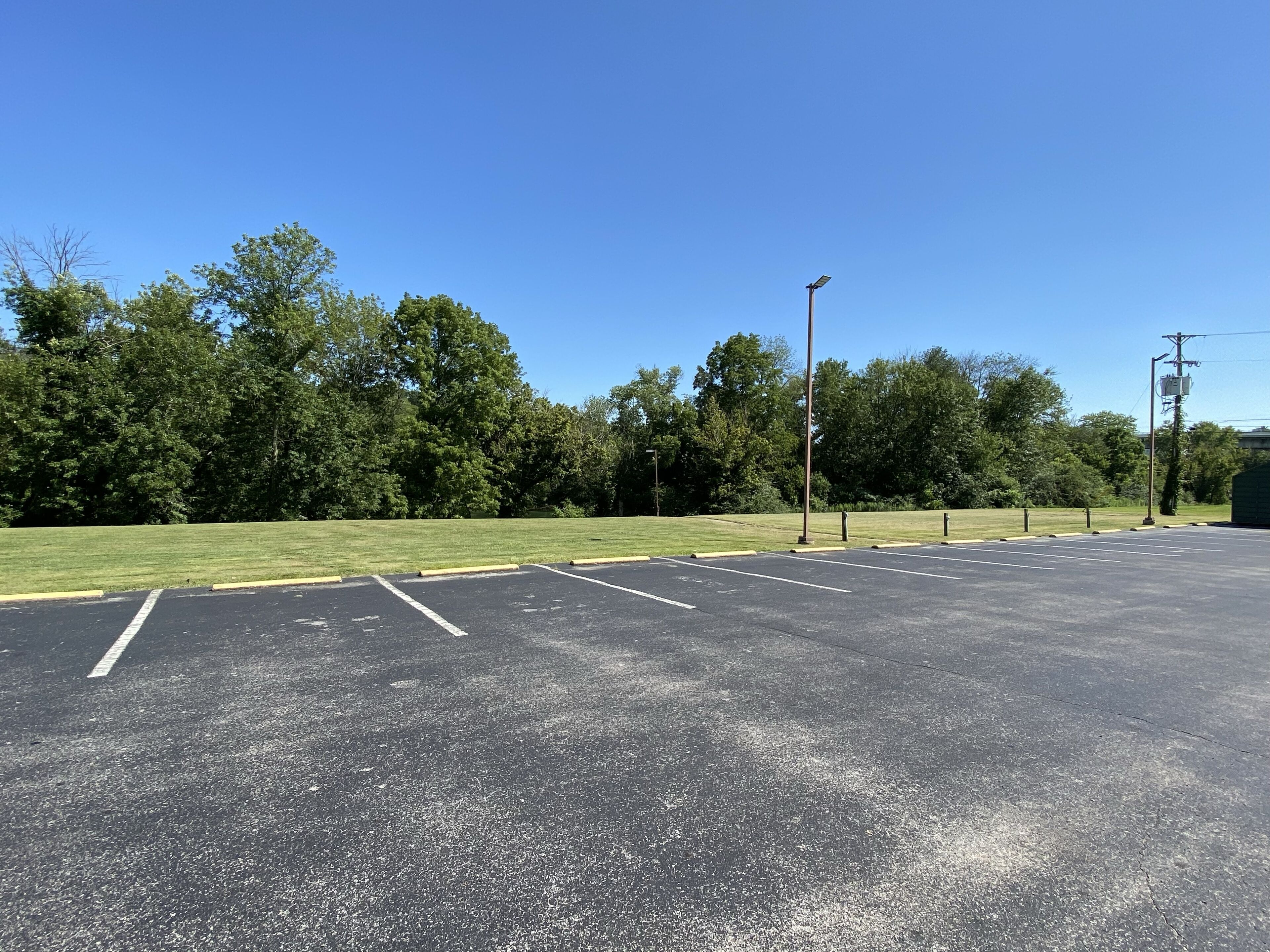 A parking lot with marked spaces and a grassy area.