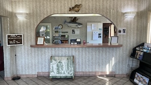A reception desk with a clock, framed photos, a calendar, and a welcome sign. - Riverfront Lodge (Burkesville)