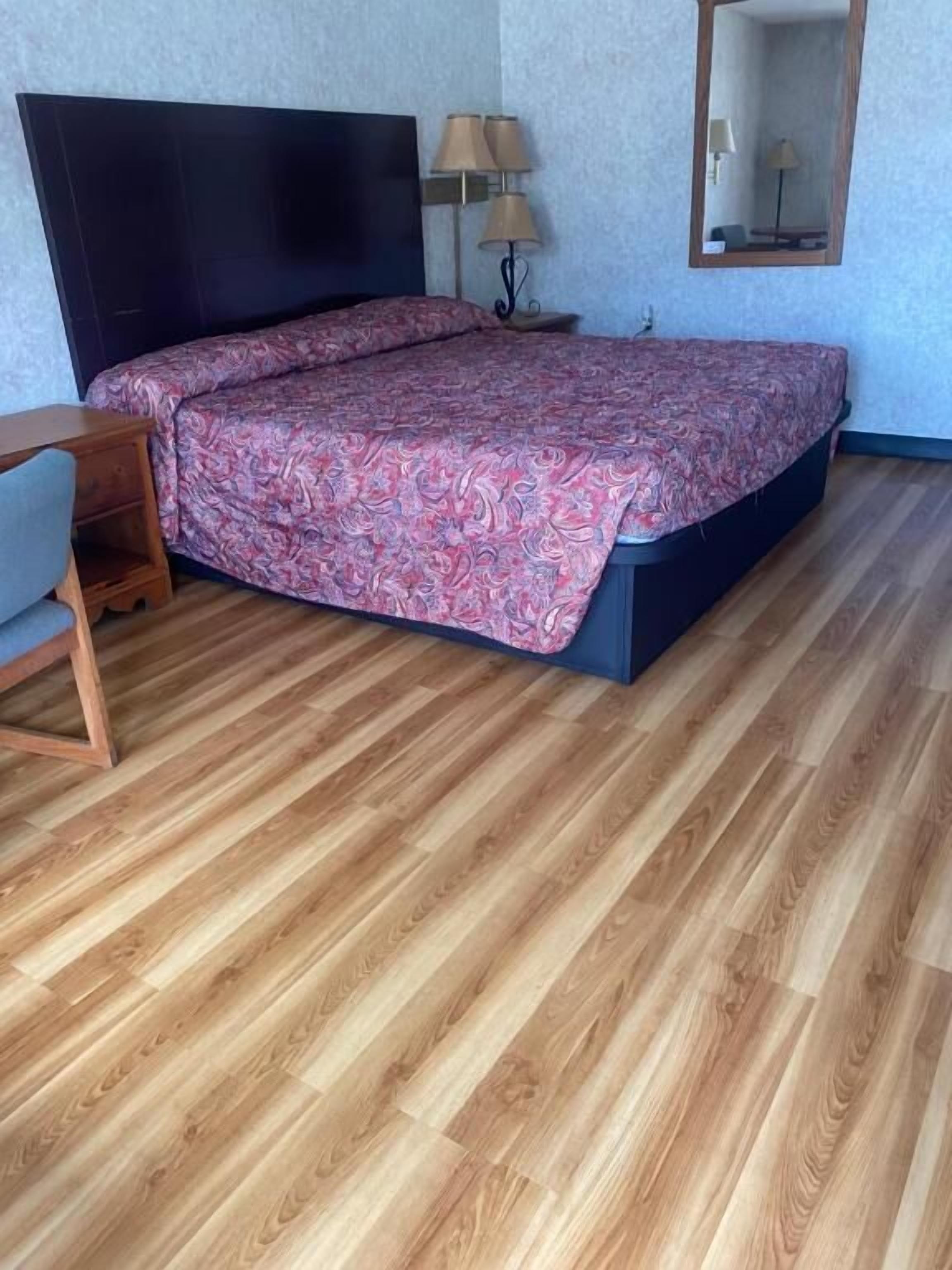 Ein Schlafzimmer mit Bett, Schreibtisch, Lampe und Spiegel.