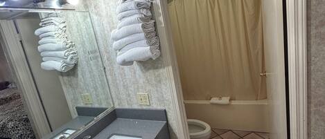 Un baño con lavamanos, espejo, toallero, inodoro y cortina de ducha.