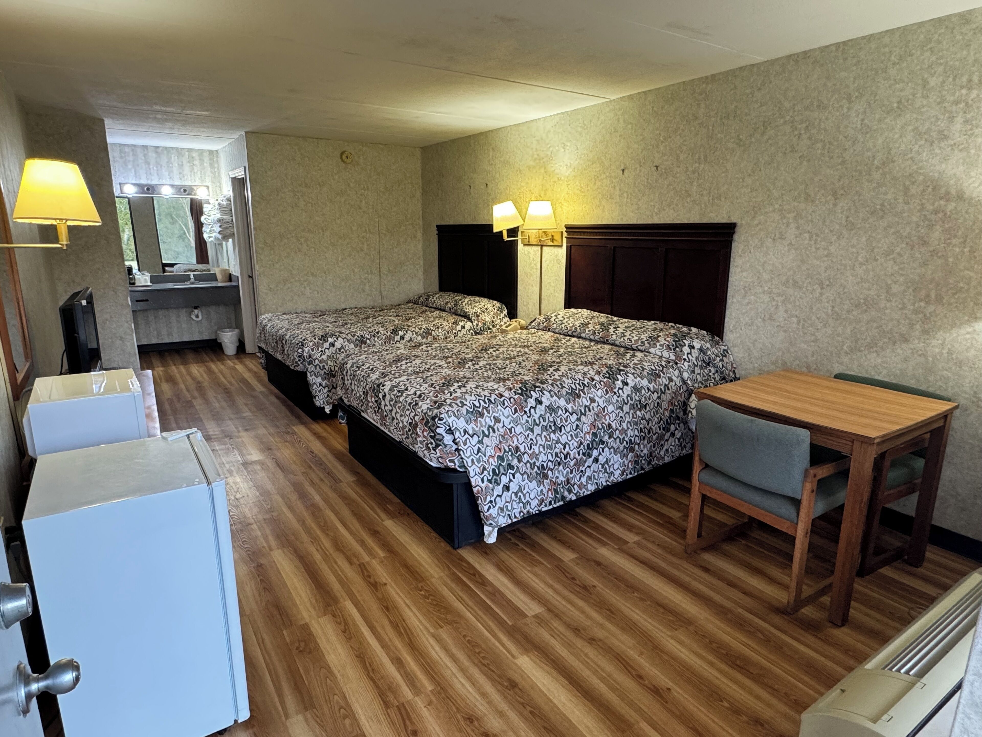 A hotel room with a bed, bedside lamps, a desk, and a chair.