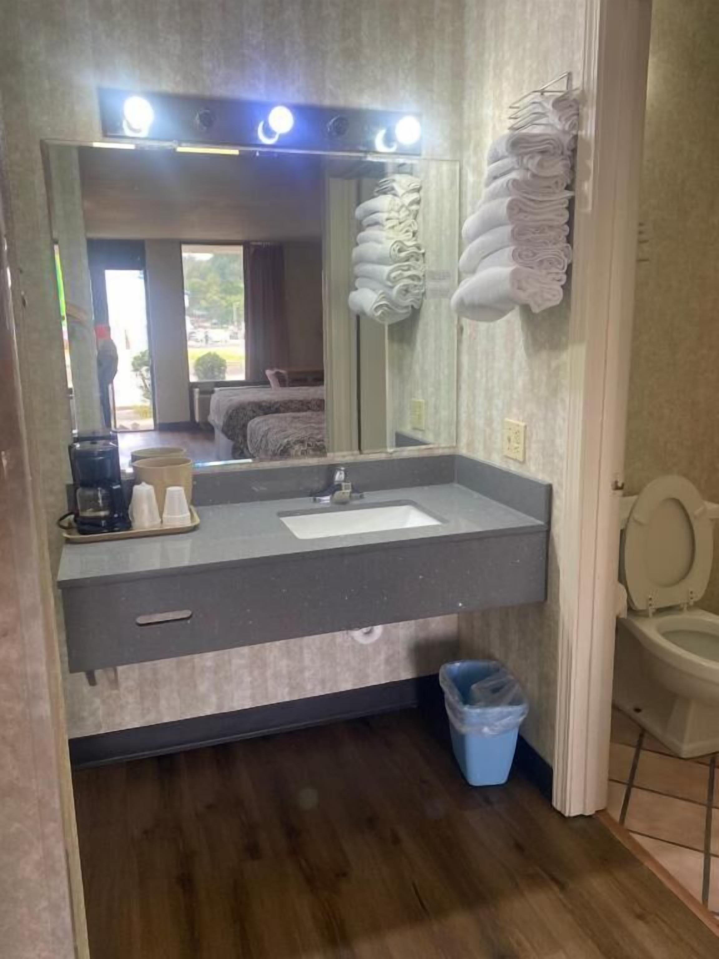 Un baño con lavamanos, espejo y perchero para toallas.