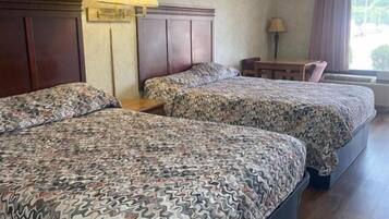 Una habitación de hotel con dos camas, un escritorio y una ventana.