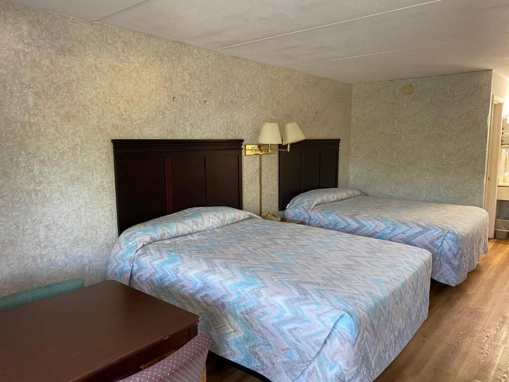 A room with two beds, a desk, and a lamp.