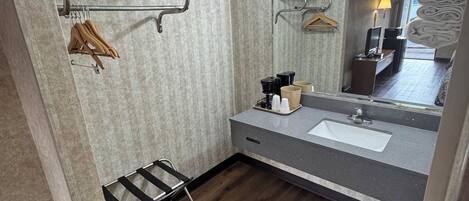 Un baño con piso de madera, un lavamanos, un espejo y un perchero para toallas.