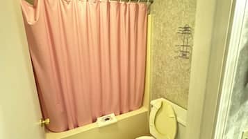 A bathroom with a toilet, a pink shower curtain, and a bathtub.