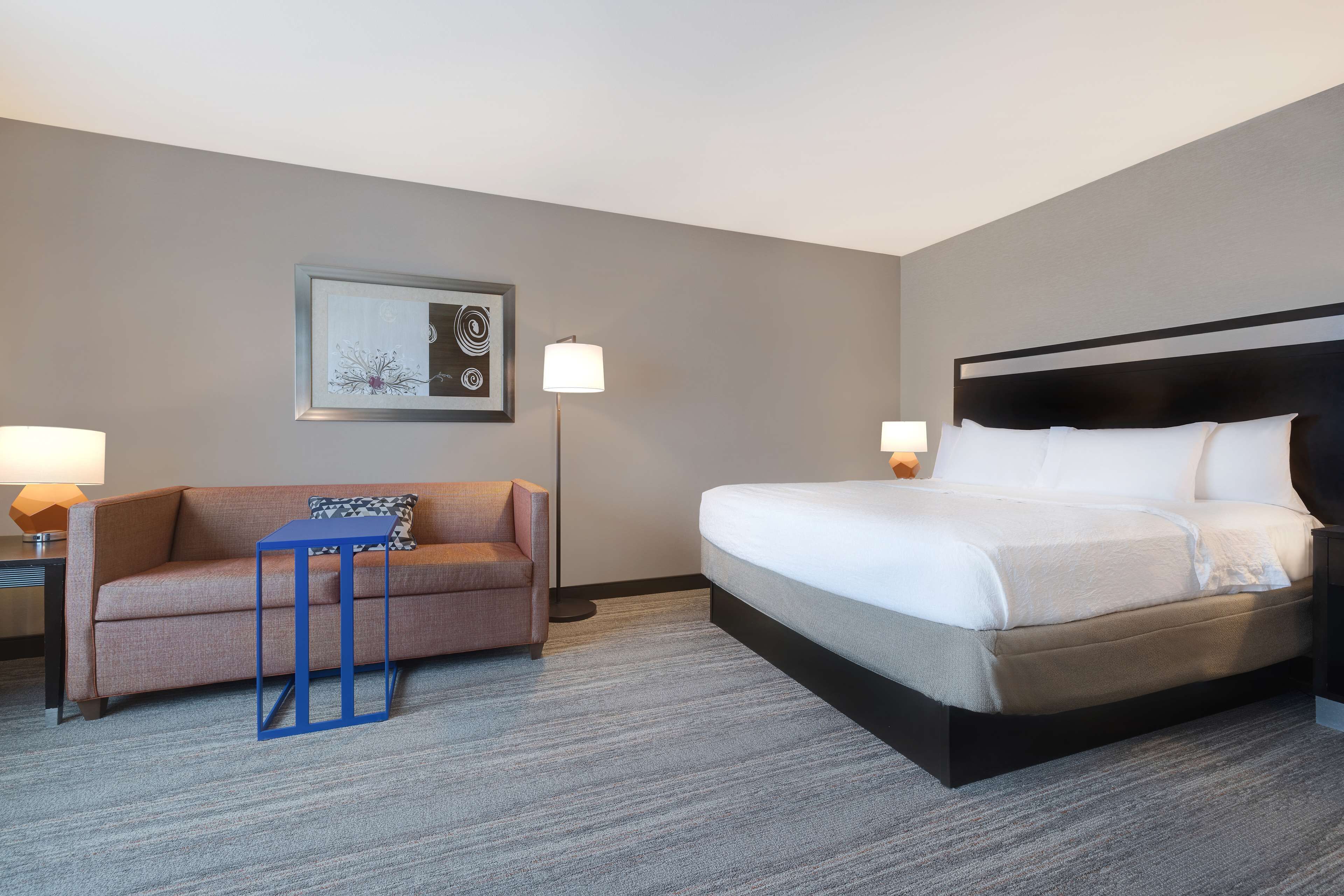 Una habitación de hotel con cama, sofá, una mesita y lámpara.