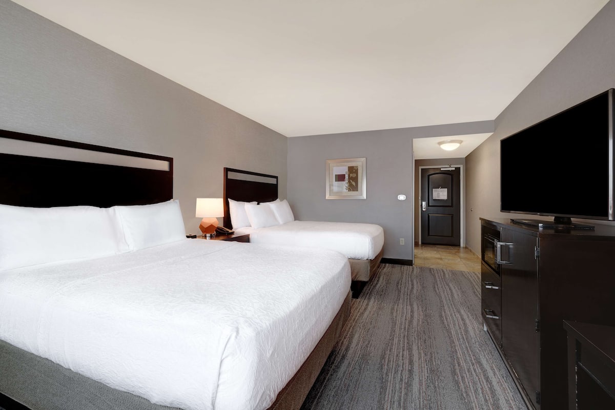 A hotel room with two beds, a television, a desk, and a wardrobe.