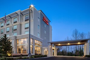 A modern hotel with a prominent sign, large windows, and a covered entrance.