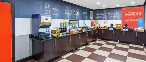 A breakfast area with a checkered floor, a waffle station, and a wall with food-related illustrations.