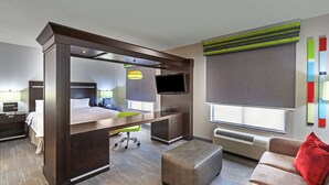 Une chambre d’hôtel avec un lit, un bureau, une chaise, une télévision et un canapé.