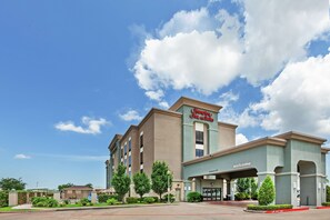 Welcome to the Hampton Inn & Suites, featuring a modern architectural design with a flat roof and a prominent entrance.