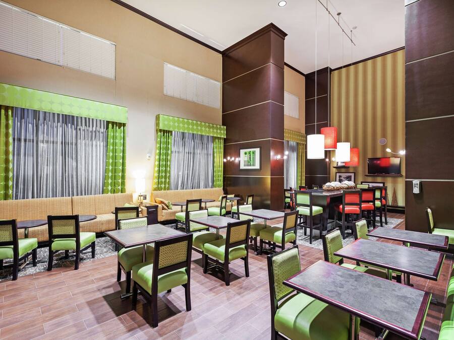 A hotel lobby with multiple seating areas, including a sofa and tables with chairs.