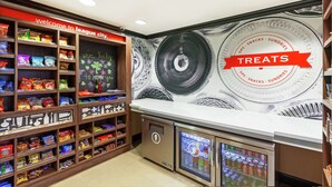 Un espace dédié à la vente de collations, avec des étagères remplies de différents types de produits et un panneau indiquant : « Bienvenue à League City. »