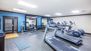 Une salle de sport  équipée de tapis de course, d’haltères et d’appareils d’exercice.